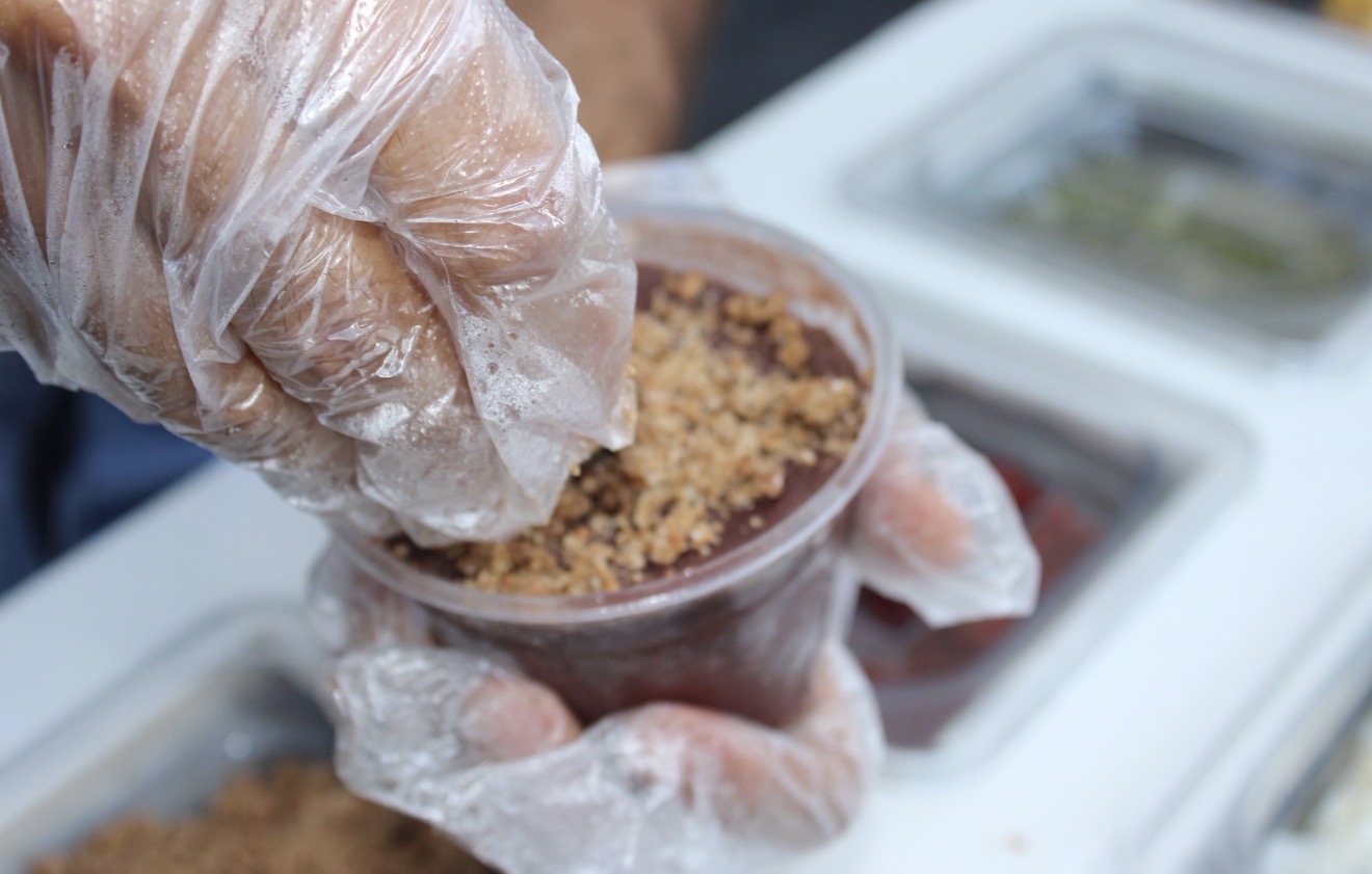 Sprinkling granola onto a fresh açaí bowl