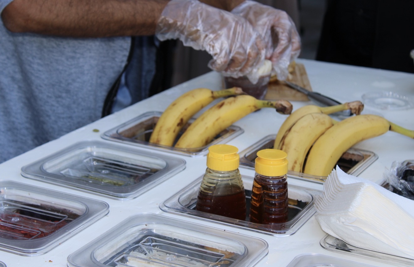 Catering setup with bananas, honey, and fresh toppings for açaí bowls