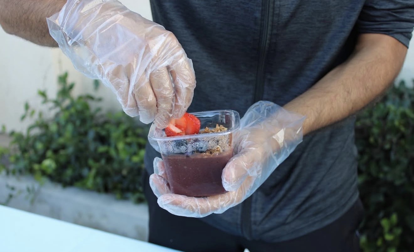 Adding fresh strawberry toppings to a handcrafted açaí bowl